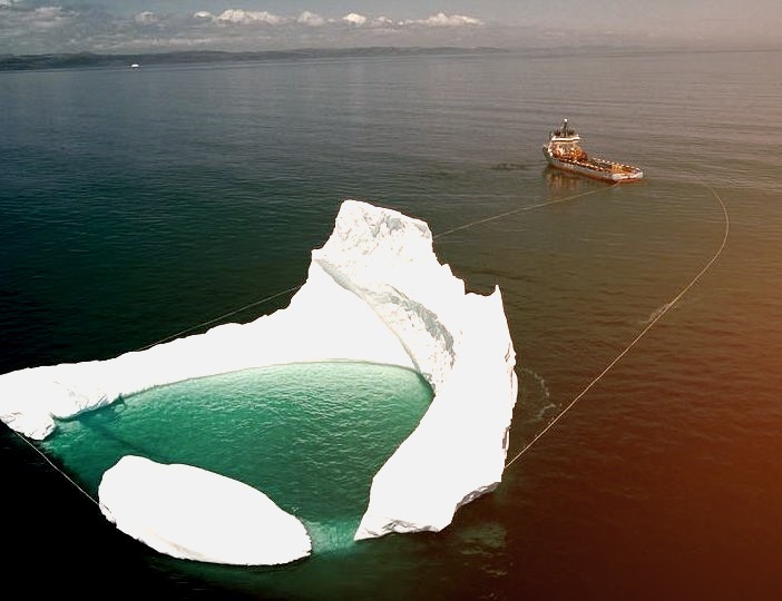 Ship towing an iceberg off the shore of Newfoundland / Canada ,